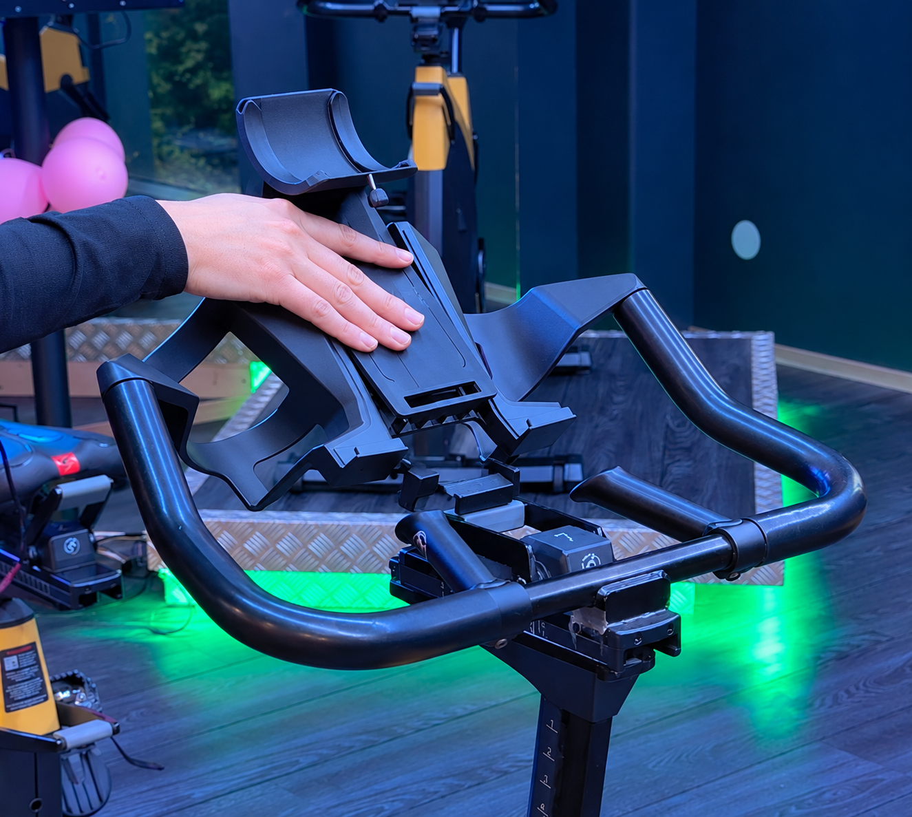 A hand securing the fan holder onto an indoor bike handlebar